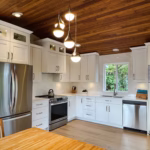 Bright white shaker kitchen with Vicostone Mangata quartz countertops, L-shape layout, and warm wood ceiling.
