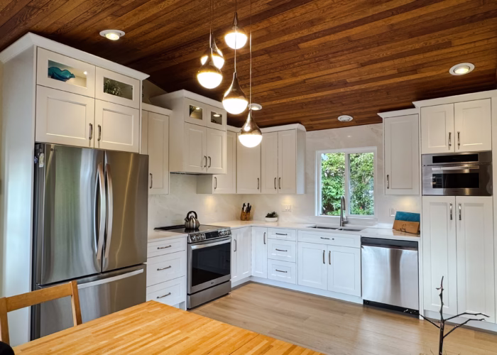 Bright white shaker kitchen with Vicostone Mangata quartz countertops, L-shape layout, and warm wood ceiling.