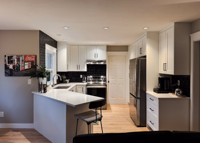 White shaker kitchen in Cloverdale Surrey with Dream White cabinets and Vicostone Polaris quartz peninsula.