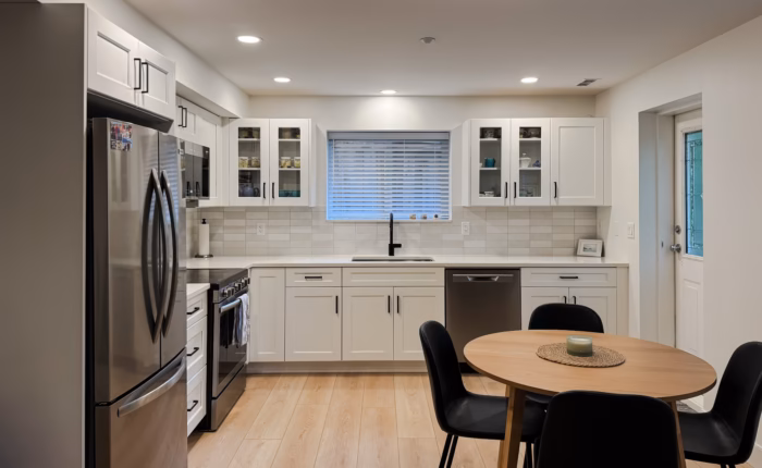 Dream White basement kitchen in Walnut Grove Langley with shaker cabinets, glass doors and dining area.